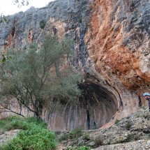Climber with the prehistoric rock shelter Cova de la Petxina close to the town Xativa